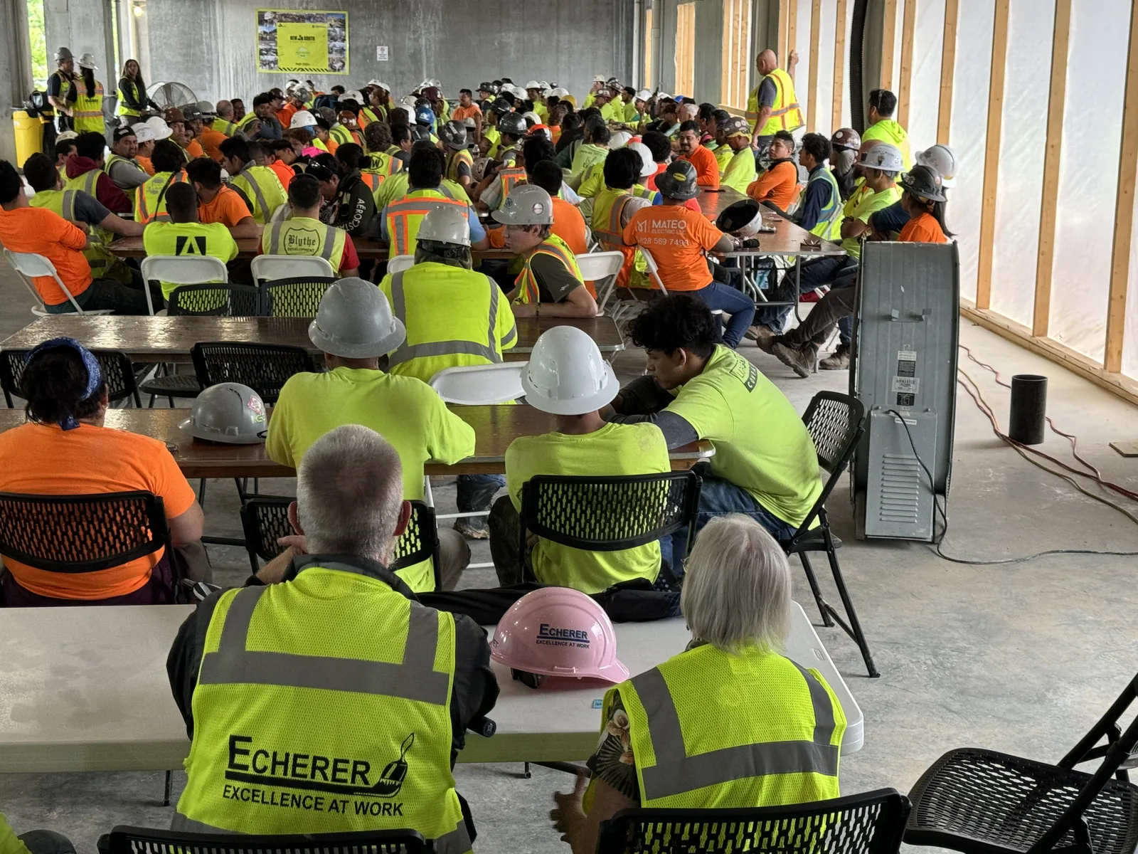 A packed jobsite safety meeting with ECHERER crew members in the foreground